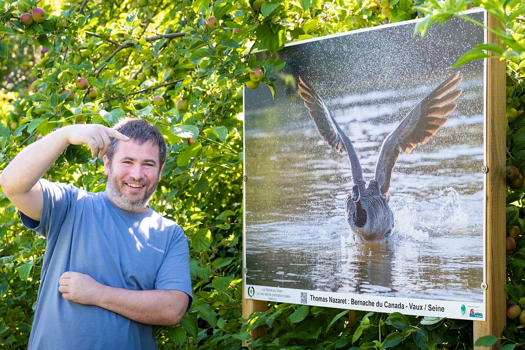 Le photographe Thomas NAZARET devant un tirage d'une de ses photos exposée en extérieur