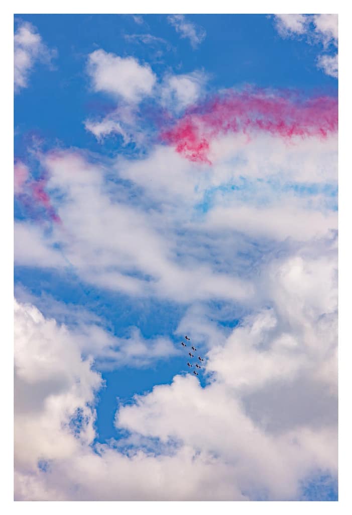 Avions apparaissant minuscules au milieu des nuages et des fumées tricolores