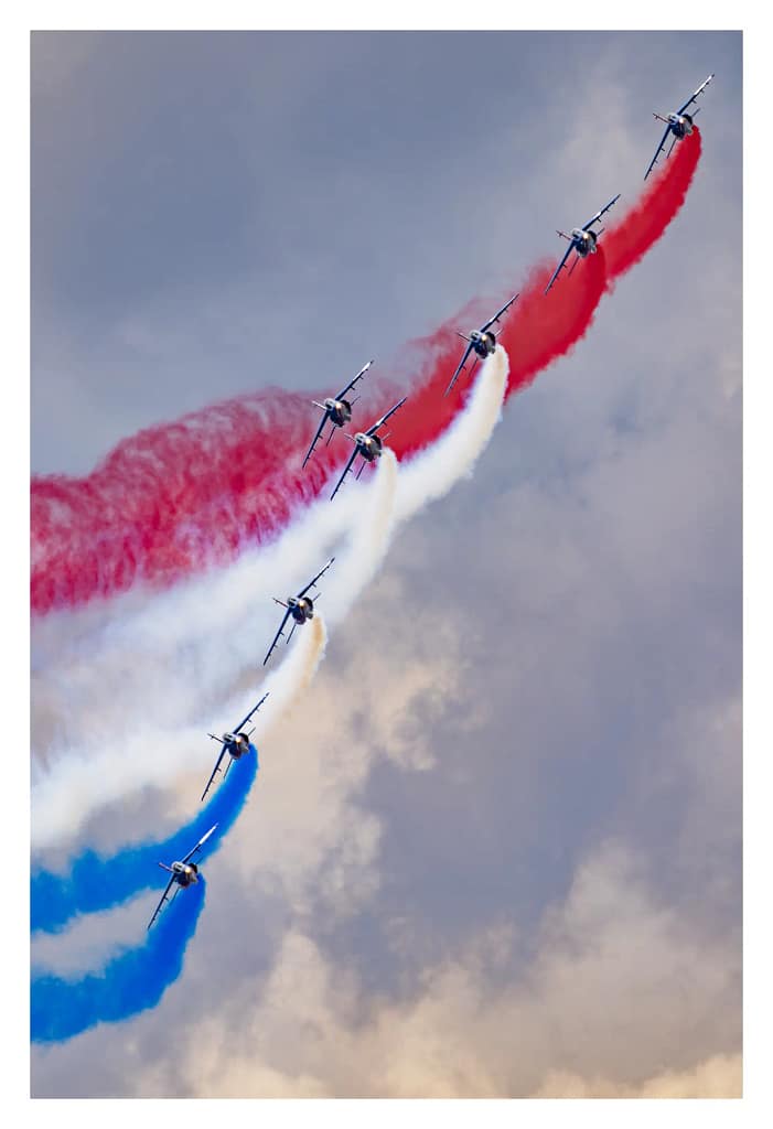 Avions de la Patrouille de France croisant leurs fumées tricolores dans le ciel