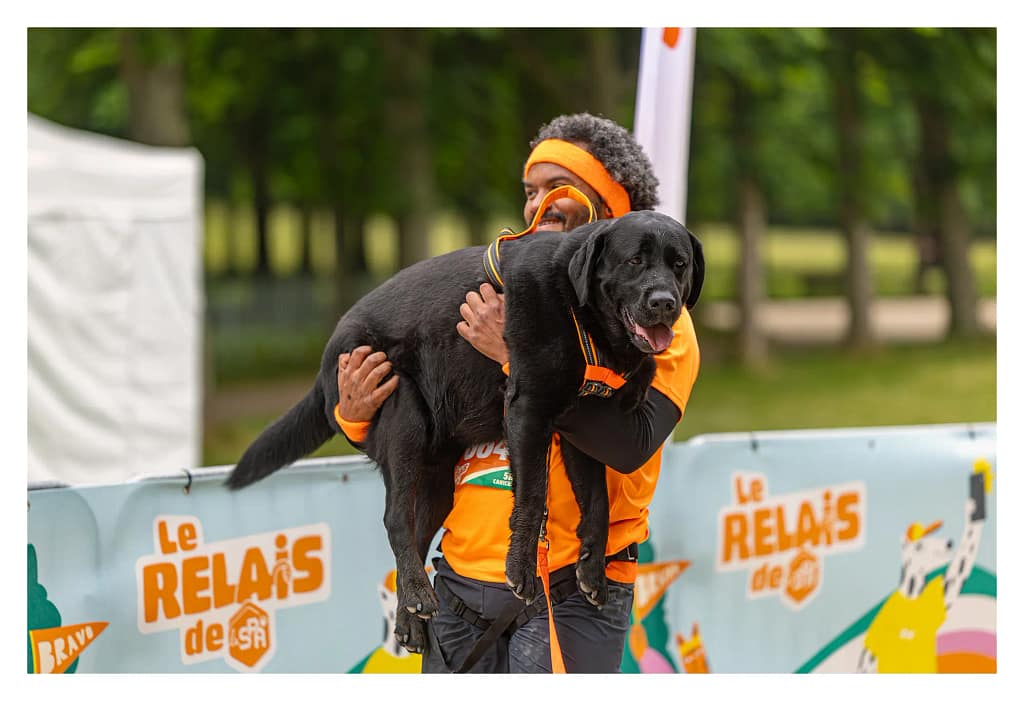 Participant au canicross deu relais de la SPA porte fièrement son chien à la fin de l'épreuve